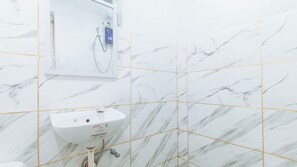Un baño con un lavamanos blanco, un espejo y una ducha con pantalla digital.