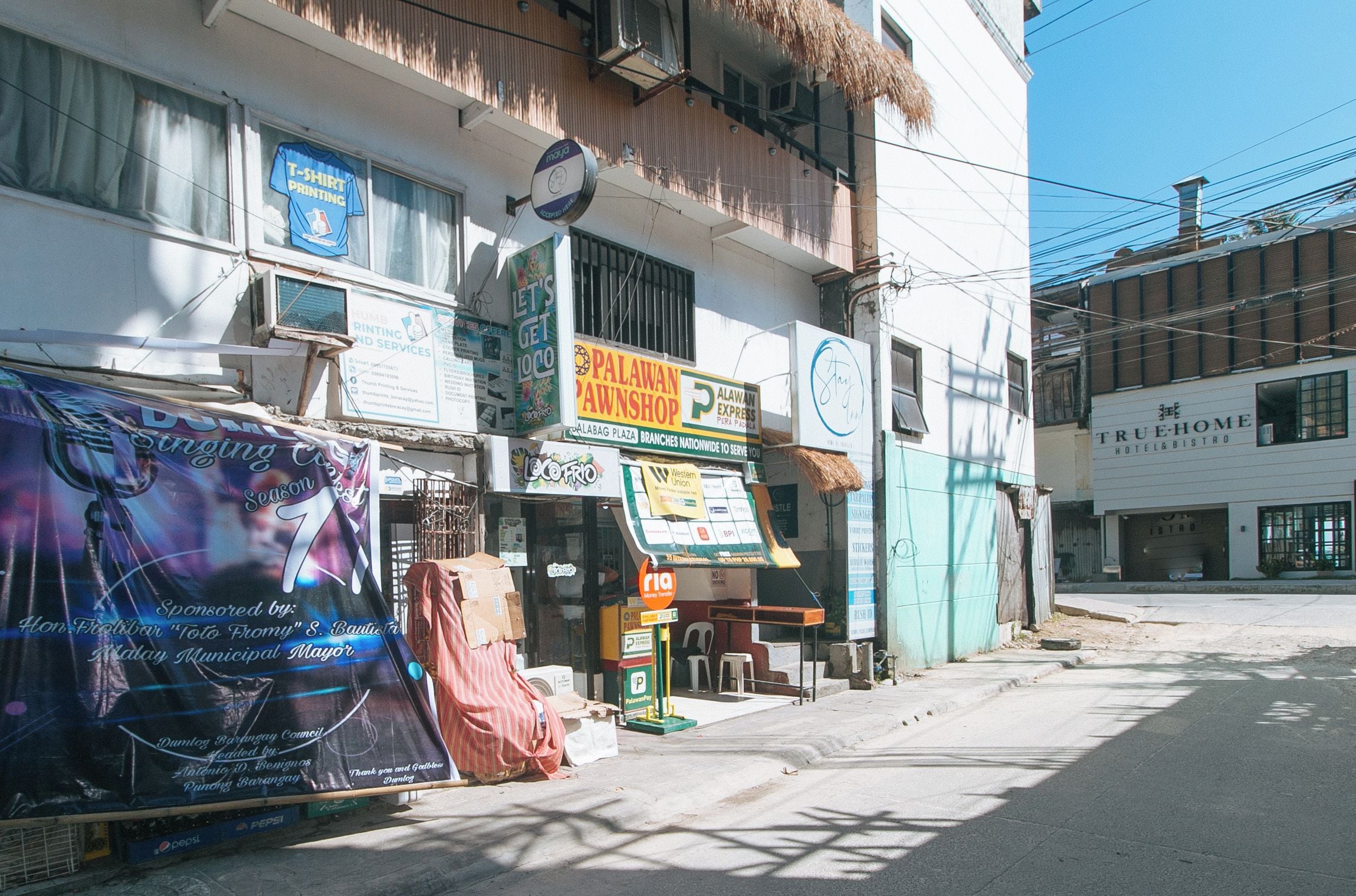 A building with multiple businesses including a printing shop, a pawn shop, and a hotel.