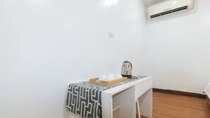 Una kitchenette pequeña con cafetera, una bandeja con tazas y un mantel estampado.