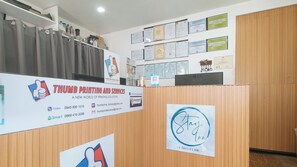 Una mesa de recepción con un cartel que indica Huellas Digitales y Servicios, una pared con certificados, y el logotipo de Stay Inn.