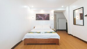 A bedroom with a wooden bed, white bedding, a painting on the wall, and a mirror. - Stay Inn Station 1 Boracay By Reddoorz (Boracay Island)