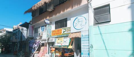 A street view of a building with multiple businesses including a printing shop, a pawnshop, and a cafe.