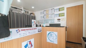 Un área de recepción con mostrador de madera, un cartel que indica Huellas Dactilares y Servicios, y una pared con varios certificados.