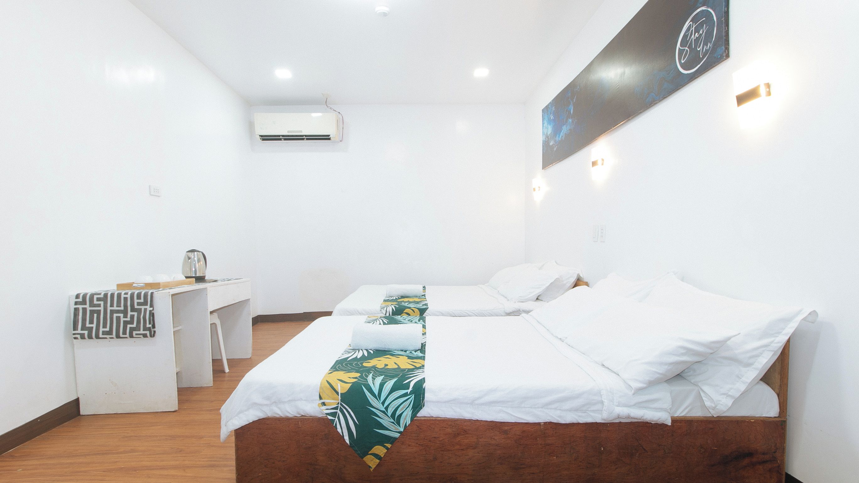 Una habitación de hotel con dos camas, un escritorio y un aire acondicionado.