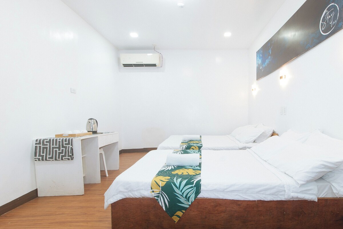 Una habitación de hotel con dos camas, un escritorio y un aire acondicionado.