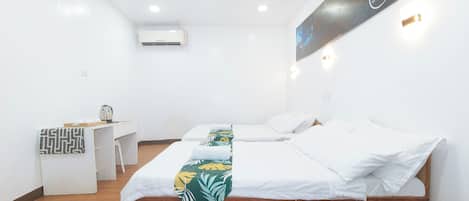 A hotel room with two beds, a desk, and an air conditioning unit.