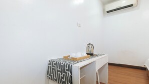 Una kitchenette pequeña con cafetera, una bandeja con tazas y un mantel estampado.