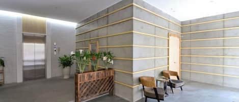 Un vestíbulo moderno con mostrador de recepción, zona de estar y una escalera.