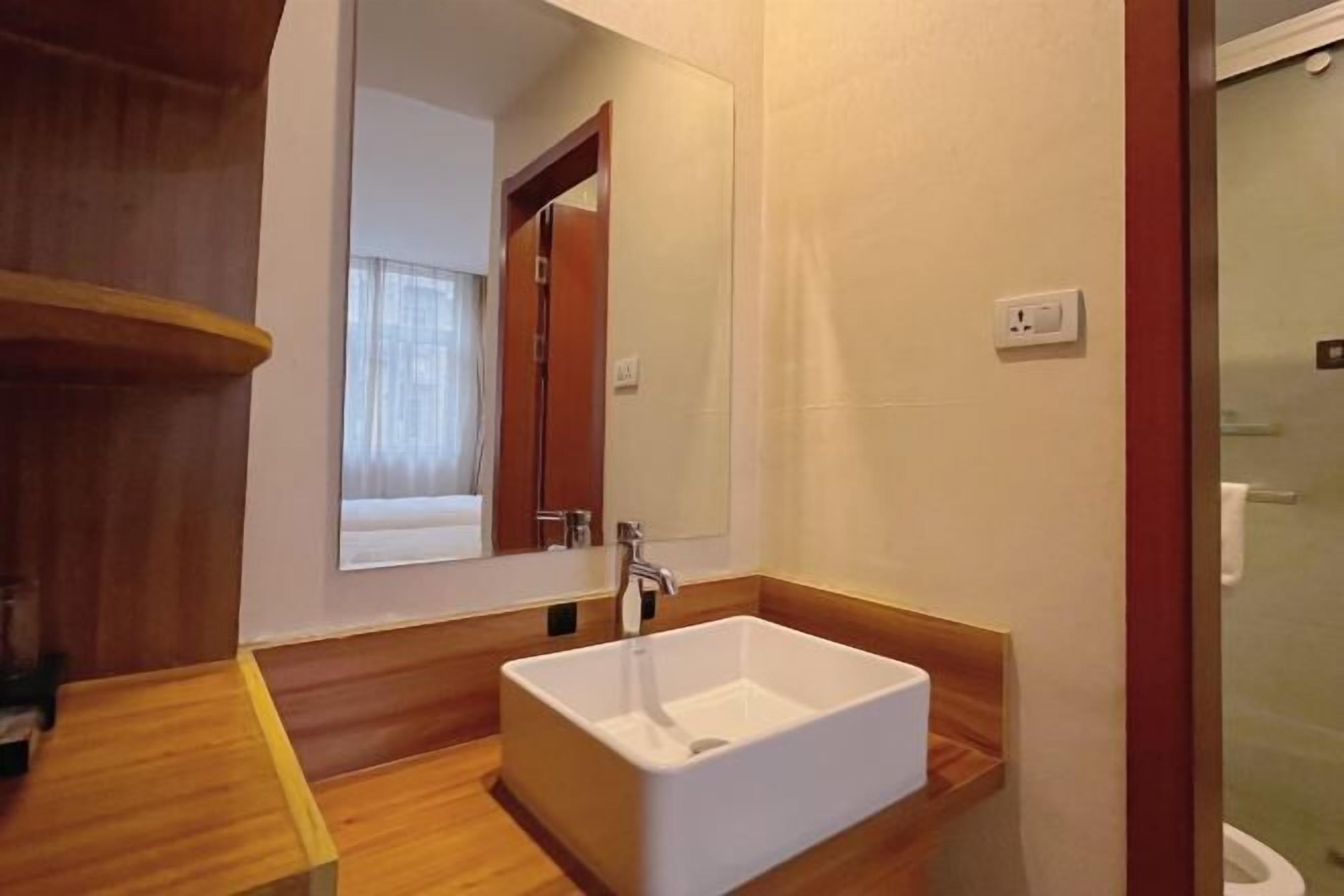 A bathroom with a white sink, wooden vanity, and a mirror.