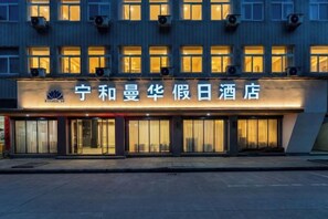Un hotel con un letrero en caracteres chinos, varios pisos y una fachada moderna.