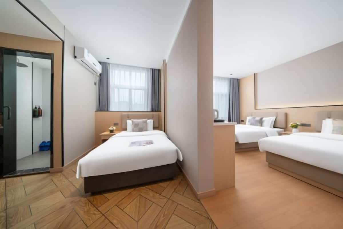 Hotellihuone, jossa on suuri sänky, pienempi sänky, työpöytä ja peili.