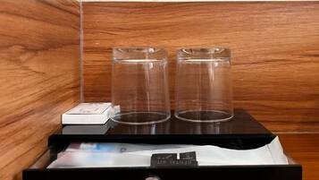 Una pared de madera con dos vasos de vidrio transparente sobre una bandeja negra.