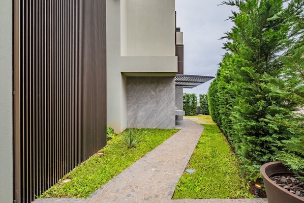 Un bâtiment moderne avec un étroit sentier, de l’herbe verte et un grand arbre.