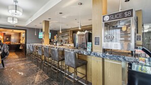 Un espace bar moderne avec un comptoir en marbre, des tabourets de bar et un panneau indiquant un prix de 8 dollars la part.