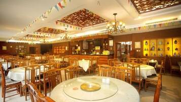 A restaurant with round tables, wooden chairs, and a central glass table.