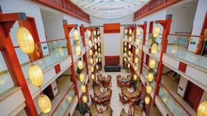 Un atrium à plusieurs niveaux, agrémenté de lanternes traditionnelles, de meubles en bois et de touches de couleur rouge.