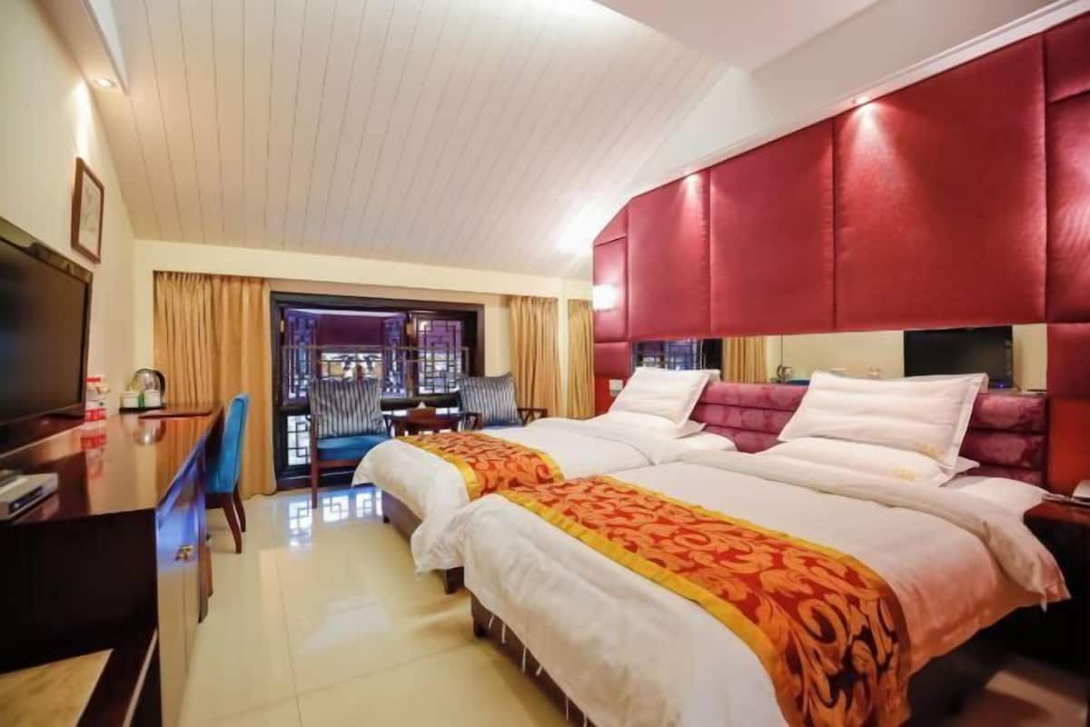 Een hotelkamer met twee bedden, een televisie, een bureau en uitzicht op buiten.