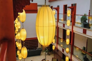 A multi-level interior with hanging lanterns, wooden railings, and a staircase.