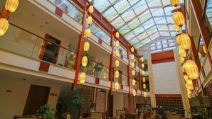 Un atrium à plusieurs niveaux, doté d’un plafond en verre, de rampes en bois et de lanternes suspendues.