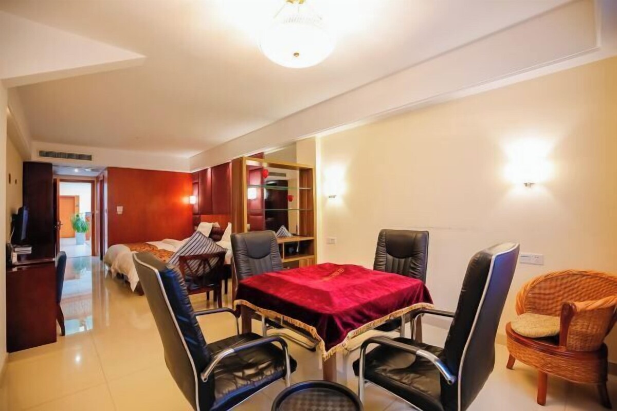 Ein Hotelzimmer mit Essbereich, einem Bett, einem Fernseher und einem Bücherregal.