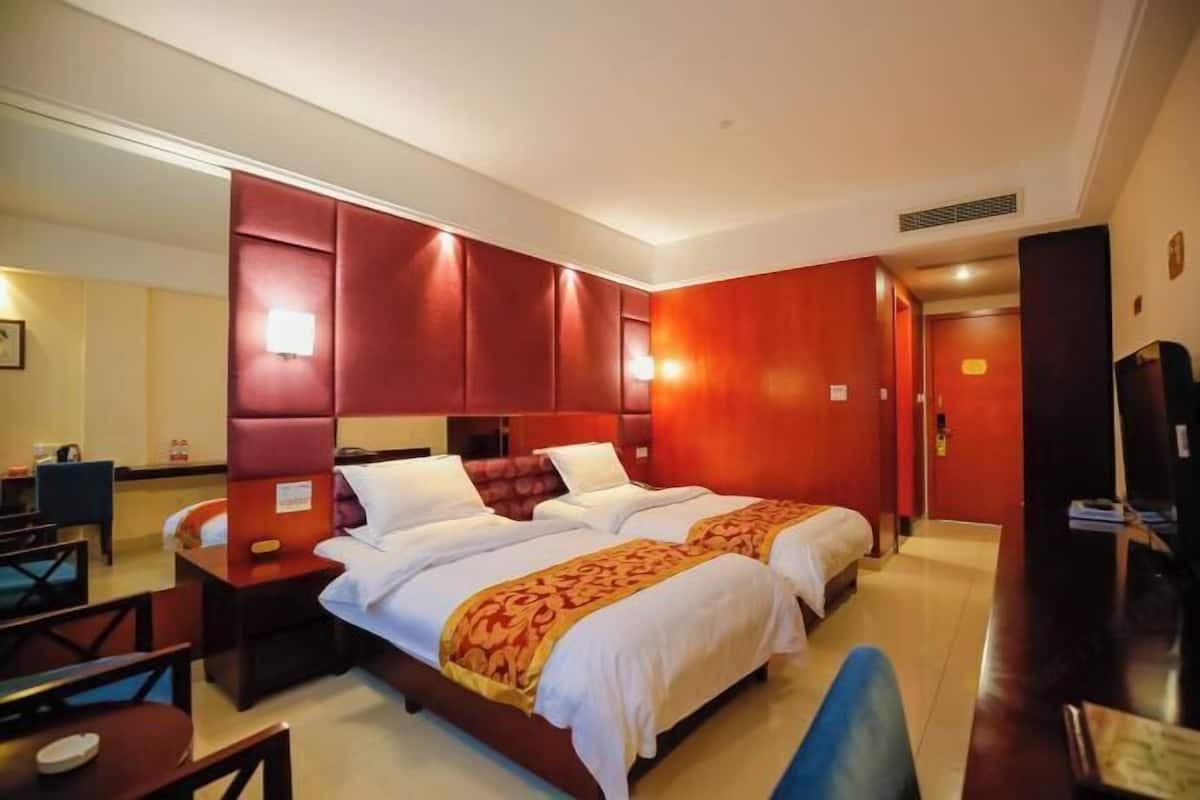 Een hotelkamer met twee bedden, een bureau en een stoel.