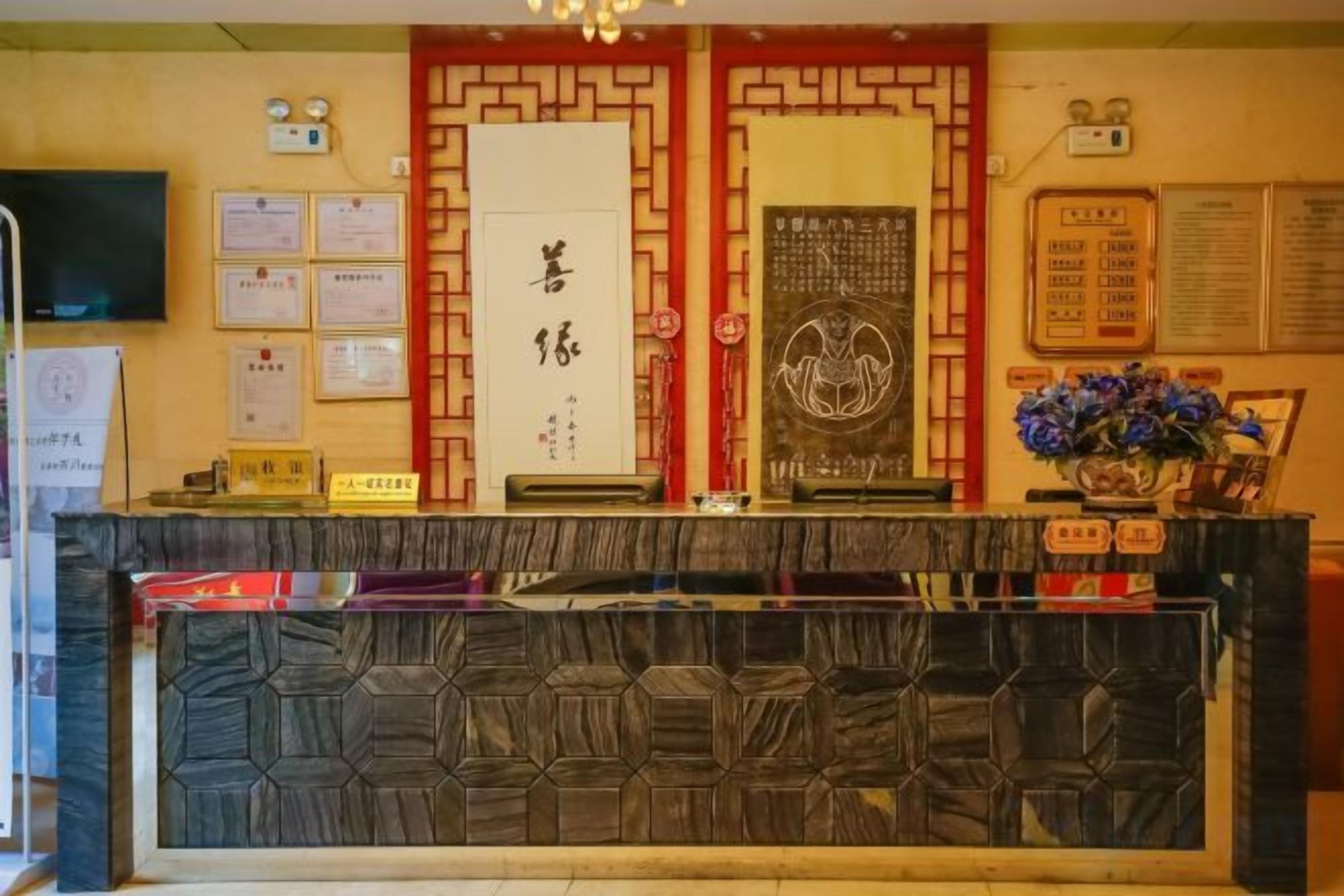 A reception area with a reception desk, framed certificates, a wall-mounted television, and a bulletin board with notices.