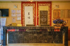 Un espace d’accueil comprenant un comptoir de réception, des certificats encadrés, un téléviseur fixé au mur et un panneau d’affichage où sont accrochées des annonces.