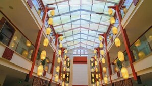 Un vaste atrium doté d’un haut plafond et d’une toiture en verre, agrémenté de lanternes suspendues et de colonnes en bois.