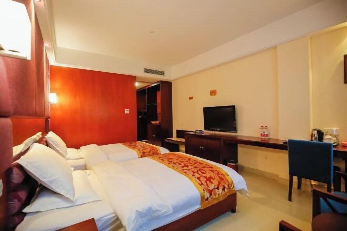 Ein Hotelzimmer mit zwei Betten, einem Schreibtisch, einem Fernseher und einem Sessel.