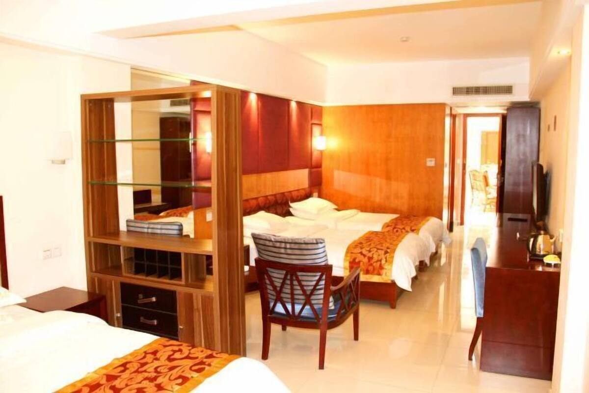 Een hotelkamer met een bed, een stoel, een bureau en een spiegel.
