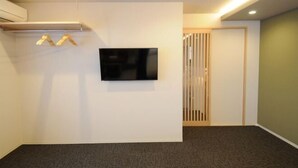 Een kamer met een aan de muur bevestigde flatscreen-tv, een deur van houten latten en een vloerbedekking.