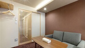 Een kamer met een bank, een tafel met een handdoek, een houten scheidingswand en een hangrek.