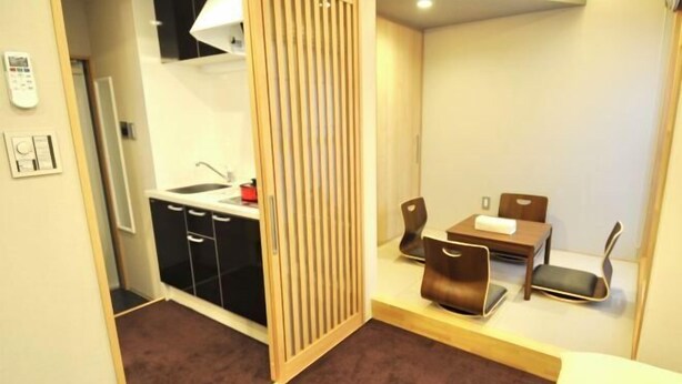 Een compacte kamer met een kitchenette, een eethoek met twee stoelen en een schuifdeur.