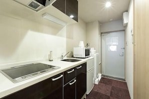 A compact kitchen with a microwave, sink, and a refrigerator.