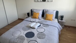 A neatly made bed with a patterned bedspread, two pillows, and a folded towel.