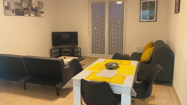 A living room with a TV, sofa, dining table, and chairs.