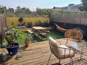 Eine Holzterrasse mit Gartenmöbeln, darunter ein Tisch und Stühle, sowie Topfpflanzen.