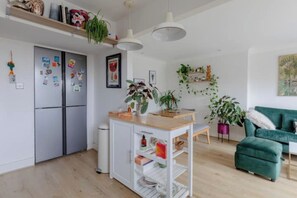 Eine moderne Küche mit weißer Arbeitsplatte, zwei Kühlschränken und einer Essecke mit einem grünen Sofa.