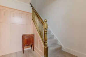 Eine Treppe mit Holzgeländer und einem kleinen Holzschrank am Fuß.