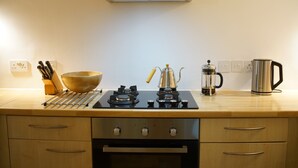 Een keuken met een fornuis, een koffiezetapparaat en een waterkoker.