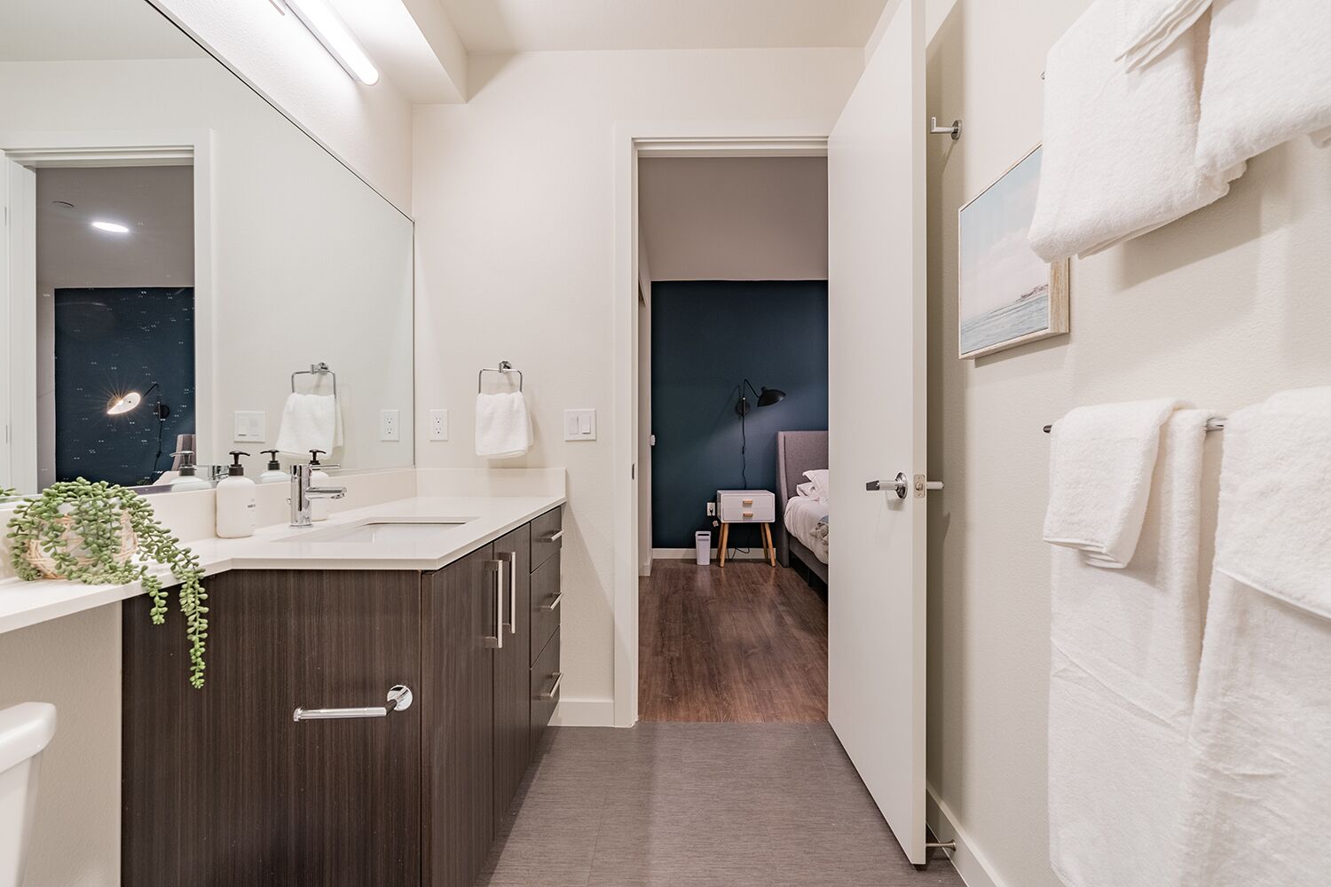 A modern bathroom with a large mirror, dark wood cabinets, and a white sink.