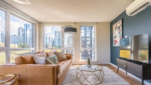 A modern living room with a leather sofa, a glass coffee table, and a flat-screen TV. - Sophari Parkside: Bellevue Apartments (Bellevue)