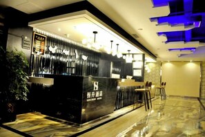 A modern reception area with a black counter, seating, and a potted plant. - Zunyi Hengsheng Hotel (Yuqing)