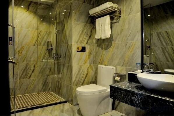 Un baño con ducha de vidrio, inodoro y lavamanos.