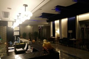 A hotel lobby with a reception desk, seating area, and large windows. - Zunyi Hengsheng Hotel (Yuqing)