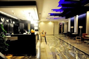 Un moderno vestíbulo de hotel con mostrador de recepción, zona de estar y suelo de mármol.