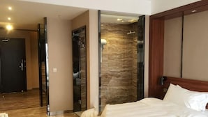 A hotel room with a bed, a mirror, a shower area, and a door leading to another room. - Zunyi Hengsheng Hotel (Yuqing)