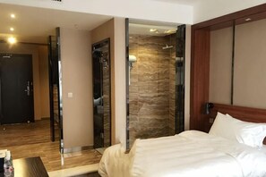 A hotel room with a bed, a mirror, a shower area, and a door leading to another room. - Zunyi Hengsheng Hotel (Yuqing)