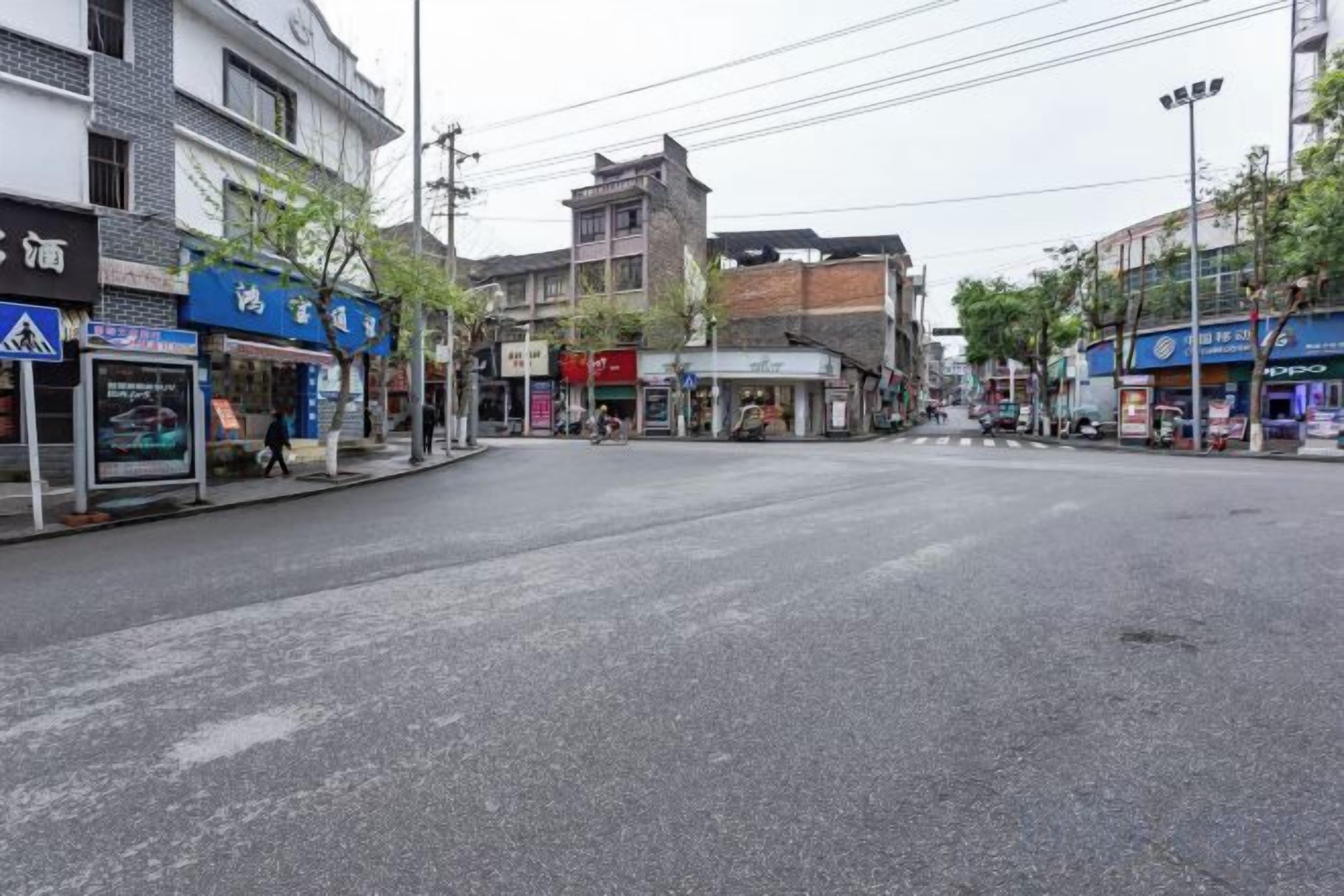 A street with buildings, a bus stop, and a pedestrian crossing.