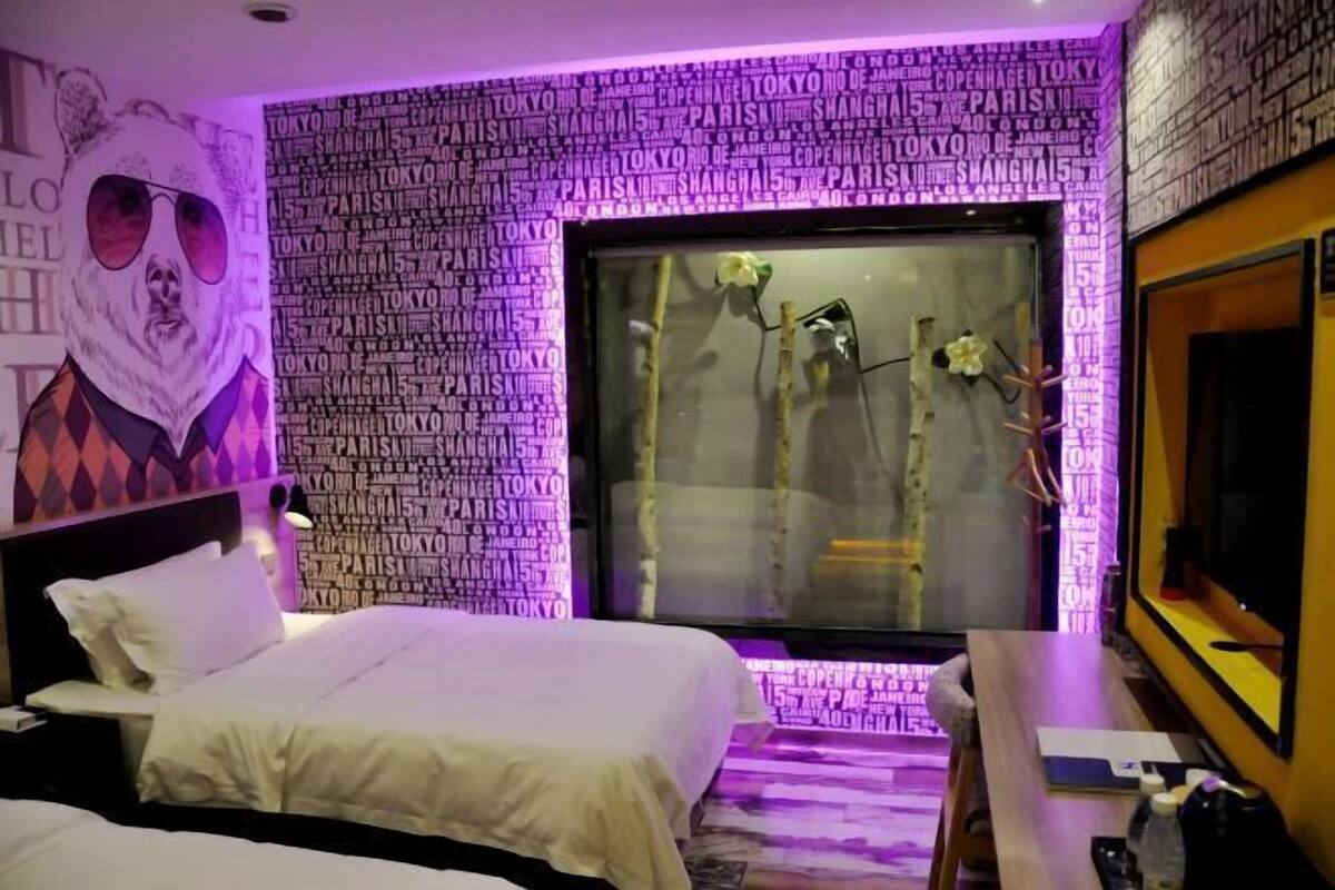 A hotel room with a bed, a desk, and a large window with a view of trees.